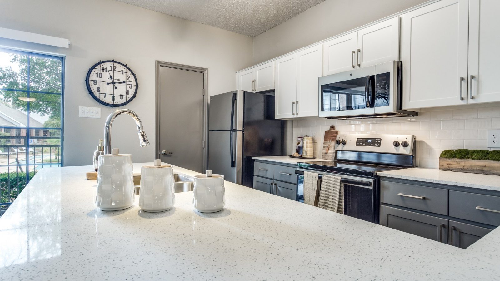 a kitchen with white counter tops and stainless steel appliances at The Hyde Park at Valley Ranch