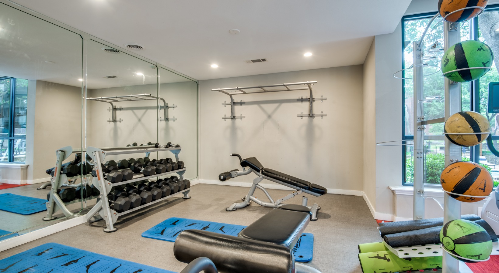 a gym room with weights, mirrors and a mirror at The Hyde Park at Valley Ranch