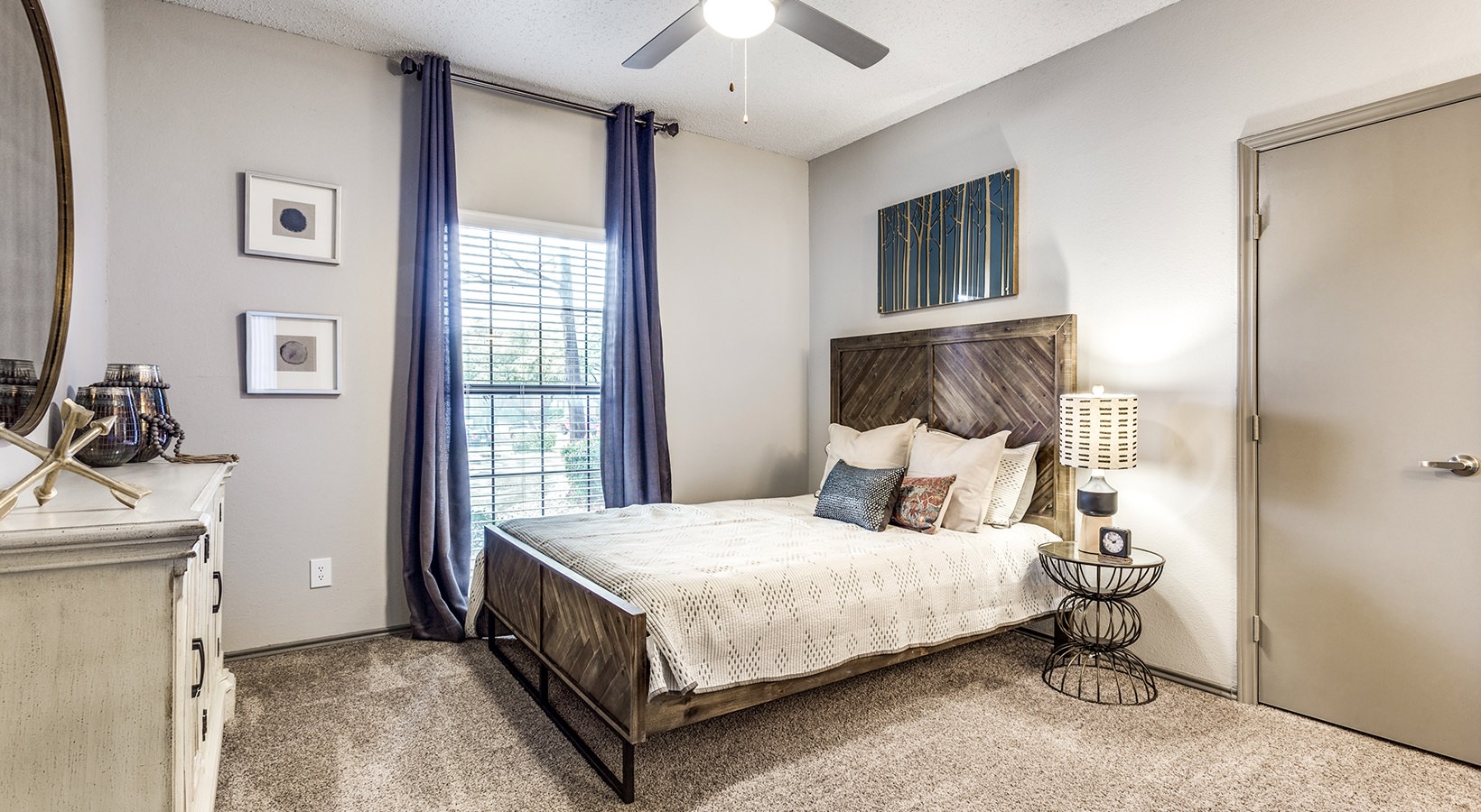 a bedroom with a bed, dresser and ceiling fan at The Hyde Park at Valley Ranch