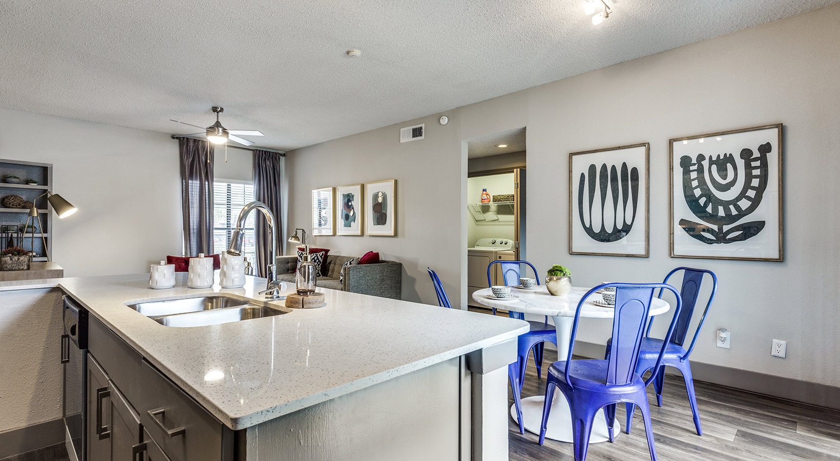 a kitchen with a sink, counter top and blue chairs at The Hyde Park at Valley Ranch