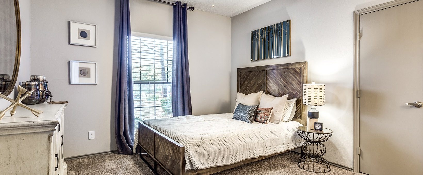 a bedroom with a bed, dresser and ceiling fan at The Hyde Park at Valley Ranch
